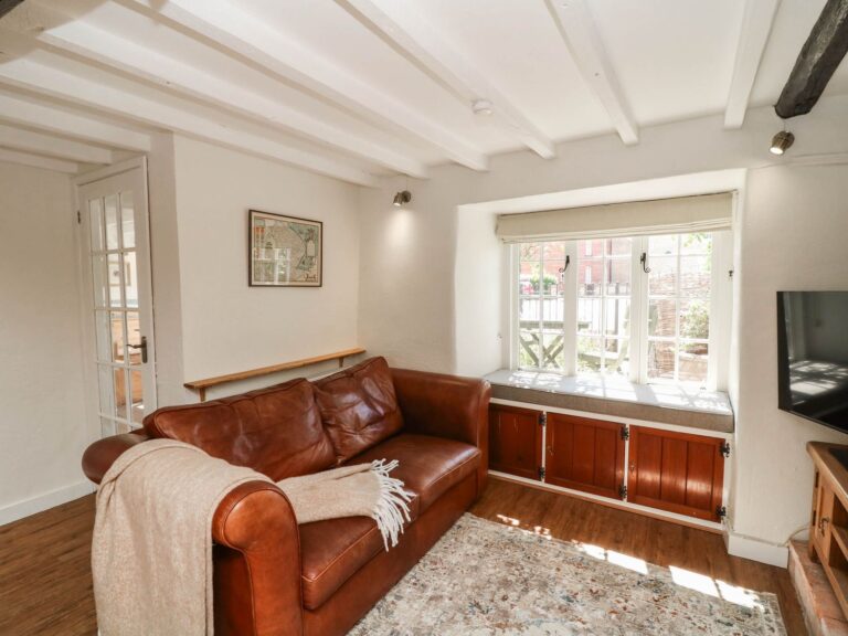 The sitting room at Freya's Cottage with leather sofa and window seat