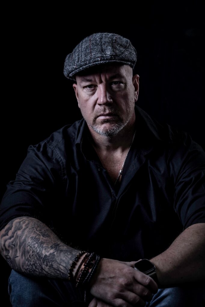 Jack Cartwright seated in a flat cap and black shirt